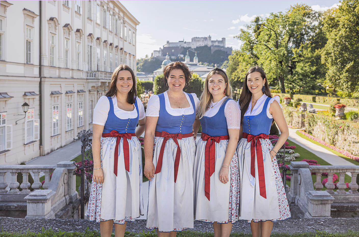 Team Salzburg Convention Bureau in Tracht im Mirabellgarten mit Blick auf die Festung.