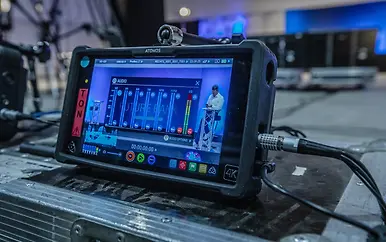 Professionelles Atomos 4K-Aufnahmegerät mit Audio-Pegelanzeige und Bildschirm, auf technischer Arbeitsplatte in blau-gedämpfter Umgebung platziert.