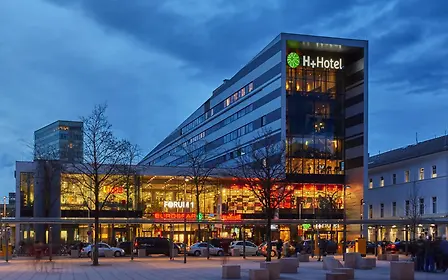 Außenansicht H+ Hotel am Salzburger Hauptbahnhof in der Nacht