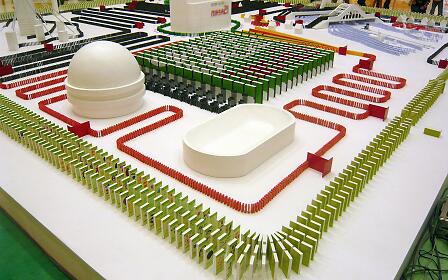 Architectural model with white sculptures, geometrically arranged red and green elements on a white surface.