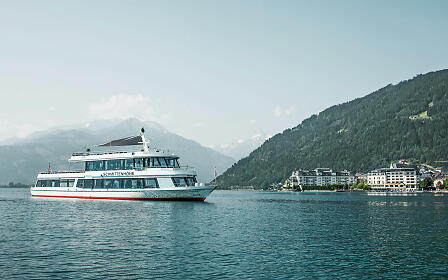 MS Schmittenhöhe bei der Schiffsfahrt am Zeller See. Im Hintergrund sieht man das Grand Hotel und Berge.