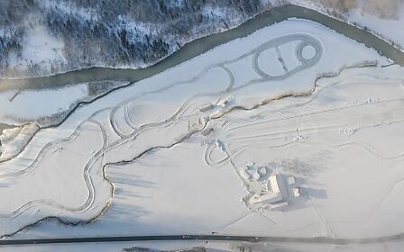 From a bird’s-eye view, the extensive grounds of the ÖAMTC Driving Technique Center Saalfelden reveal multiple snow-covered training courses. Curving tracks, practice areas and buildings are embedded within a calm alpine winter landscape.