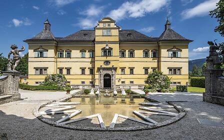 Hellbrunn Palace, a baroque pleasure palace just outside Salzburg, impresses with its bright yellow façade, playful fountains and sculpted gardens. The pond with classical statues in front adds a fairytale charm to this historical site.
