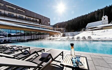 Beheizter Außenpool im aja Bergresort Werfenweng bei strahlendem Sonnenschein im Winter