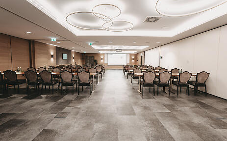 Leerer Konferenzraum mit grauen Stühlen, weißer Decke und modernem Design im Seminar Hotel Hubertushof in Anif.