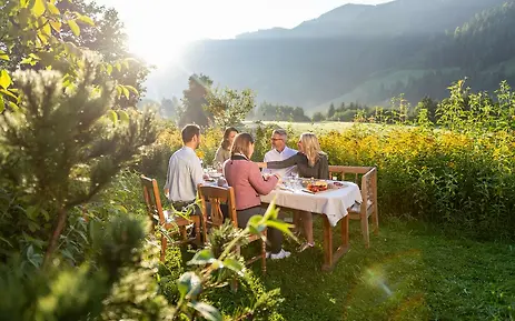 Friends enjoying breakfast in picturesque mountain landscape with sunlight and lush vegetation in SalzburgerLand.