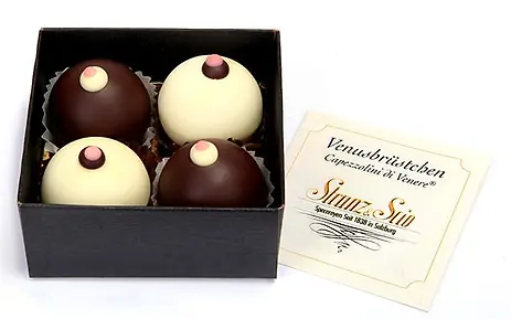 Vier elegante Schokoladenkugeln in weißer und dunkler Schokolade in einer schwarzen Geschenkbox, daneben eine Visitenkarte.