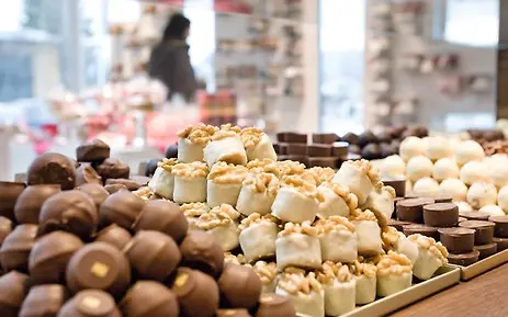 Nahaufnahme einer Schokoladentheke mit verschiedenen Pralinen und Konfektstücken in unterschiedlichen Braun- und Weißtönen, arrangiert auf Holzablagen.