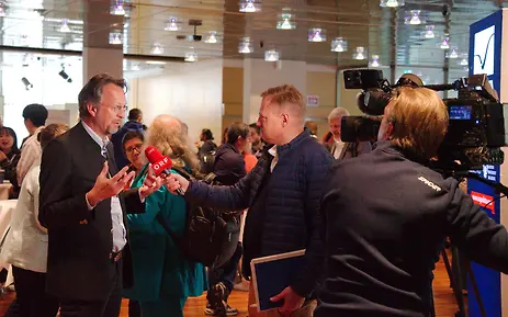 Press conference with interviews at the University of Salzburg. A speaker is answering questions from journalists and camera teams.