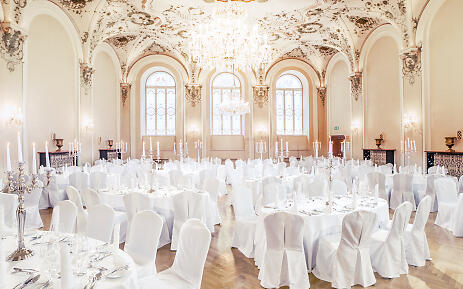 Prunkvoller Festsaal mit barocker Deckengestaltung, weiß gedeckten Tischen und eleganten Kronleuchtern im historischen Ambiente des St. Peter Stiftskulinariums.