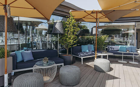 Modern outdoor terrace with stylish lounge furniture, parasols and plants - offers guests a relaxed outdoor seating area for meetings, meals or events in an urban atmosphere with a view over Salzburg's old town. Outdoor lounge area with seating for guests - suitable for relaxation and socializing.