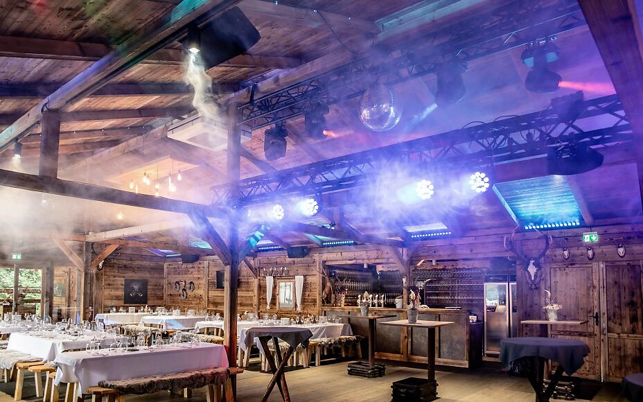 Rustikale Holzscheune mit festlicher Beleuchtung und gedeckten Tischen, ausgestattet mit professioneller Veranstaltungstechnik und atmosphärischen Lichteffekten.