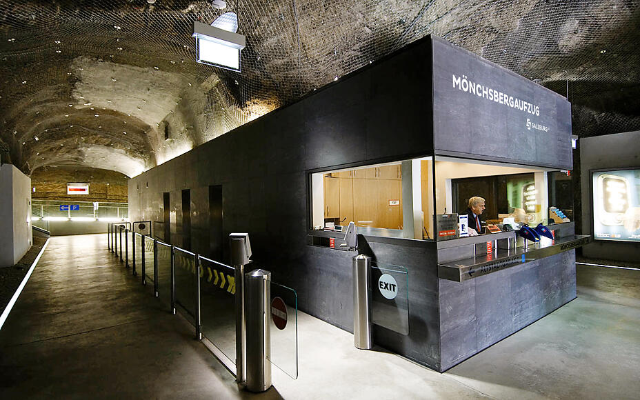 Unterirdischer Aufzugbereich des Mönchsbergaufzugs in Salzburg mit moderner Empfangstheke und gewölbter Tunnelarchitektur.