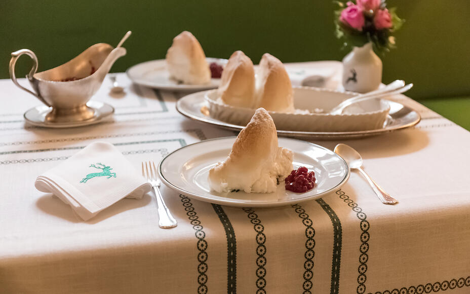 Golden Salzburg Nockerl served with lingonberries and silver cutlery on an elegant table.