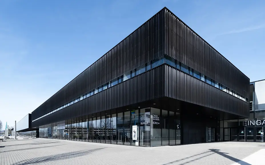 Die moderne Fassade des Messezentrums Salzburg überzeugt mit klarer Linienführung, dunklen Lamellen und großzügiger Glasarchitektur. Weitläufiger Eingangsbereich für Besucherströme.