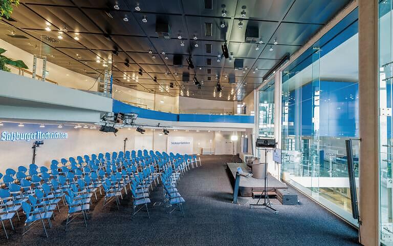 Modern conference room with blue chairs, glass facade, and ceiling lighting in a bright, contemporary building.