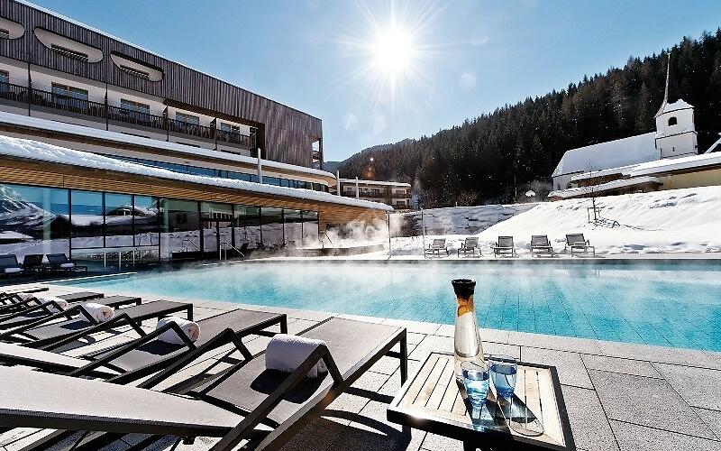 Beheizter Außenpool im aja Bergresort Werfenweng bei strahlendem Sonnenschein im Winter